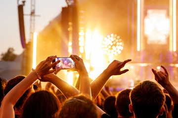 Making video of concert using a smartphone. Cheering people on an amazing music show.