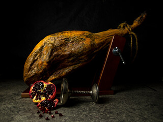 whole leg of jamon with pomegranate on black background - 564314466