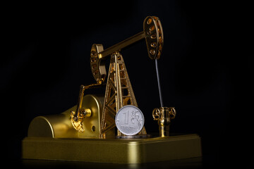 Model of a golden oil pump and a 1 Russian ruble coin on a black background