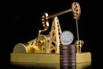 Model of a golden oil pump and a 1 Russian ruble coin on a black background