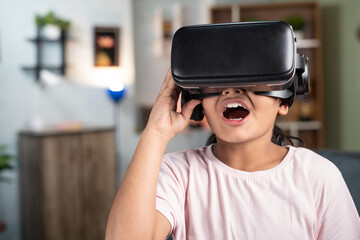 Excited girl kid with VR or vertual reality headset experiencing metaverse at home - concept of immersive experience and modern technology