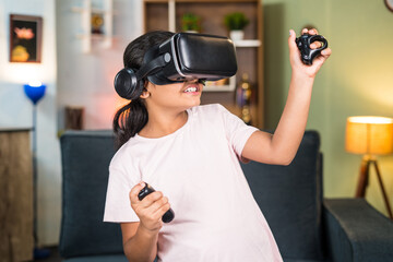 Girl child with VR or vertual reality goggles and joystick in hands playing video game on metaverse at home - concept of immersive experience, technology and entertainment © WESTOCK