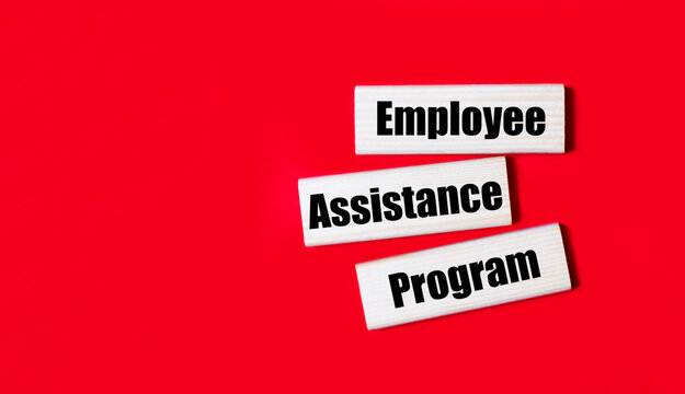 Three wooden blocks with the text EAP Employee Assistance Program on a bright red background. Copy space