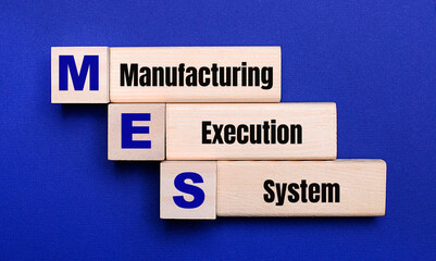 On a bright blue background, light wooden blocks and cubes with the text MES Manufacturing Execution System