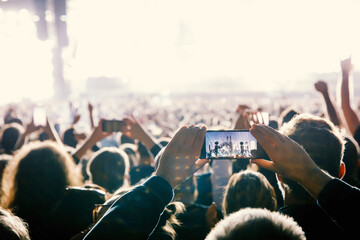 Making video of concert using a smartphone. Cheering people on an amazing music show.