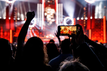 Fototapeta na wymiar Making video of concert using a smartphone. Cheering people on an amazing music show.