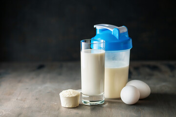 Protein shake in bottle, powder, bars, eggs and measuring tape on dark background.  Sport food...