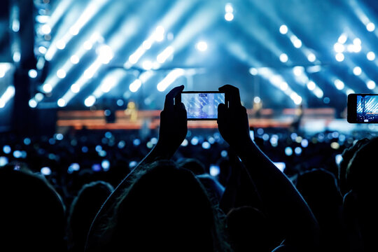 Making video of concert using a smartphone. Cheering people on an amazing music show.