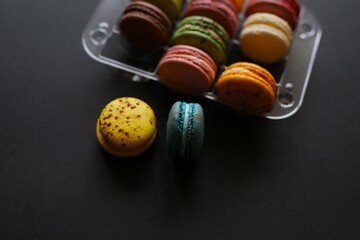 delicious macaroons, multi-colored, of various flavors, in a transparent package, lie on a black or white background. homemade homemade macaroons