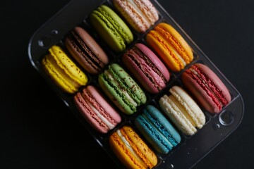delicious macaroons, multi-colored, of various flavors, in a transparent package, lie on a black or white background. homemade homemade macaroons