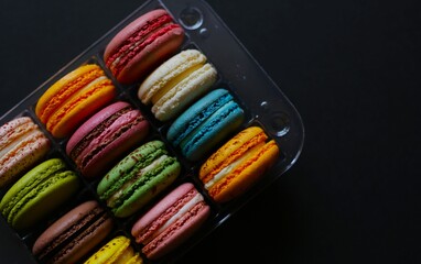 delicious macaroons, multi-colored, of various flavors, in a transparent package, lie on a black or white background. homemade homemade macaroons