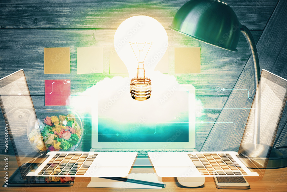 Poster Computer on desktop in office with bulb icon hologram. Double exposure. Concept of idea.