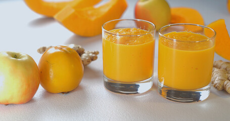 Pumpkin and ginger smoothie into glasses against a background of fresh vegetables and fruits