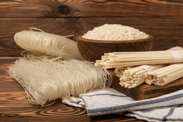 Fototapeta na wymiar Rice noodles.Rice and noodles with rice flour in a wooden plate on a brown wooden background.Close-up. Place for text. Copy space.