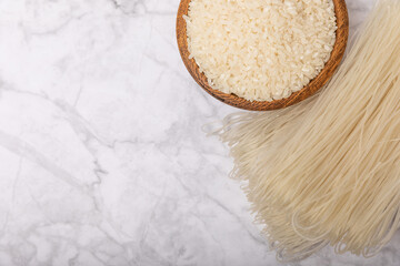 Rice noodles.Rice and noodles with rice flour in a wooden plate on a white marble background.Close-up.Useful and healthy food. Place for text. Copy space.