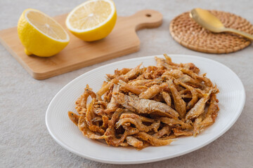 Crispy fried small fish on white plate