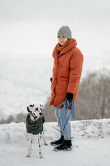 Warm angezogene Frau mit jungen Dalmatiner im Schnee während des Winters mit Ausblick auf Heidelberg
