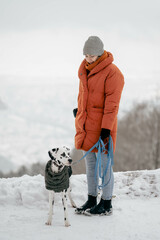 Warm angezogene Frau mit jungen Dalmatiner im Schnee während des Winters mit Ausblick auf Heidelberg