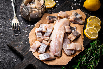 Fillet of salted herring on paper on a cutting board. 