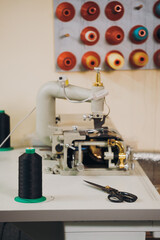 Spool of threads. Colorful thread spools hanging on the wall in fabric and textile industry manufacturing. Sewing machine on the table. Tailoring and small business concept 