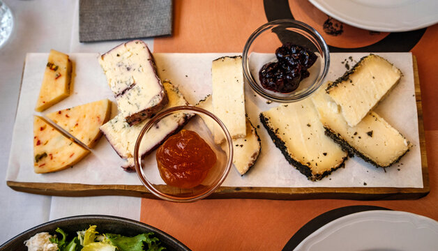 Cheese board with jam on the table in the restaurant, top view. Antipasto platter at Italian restaurant