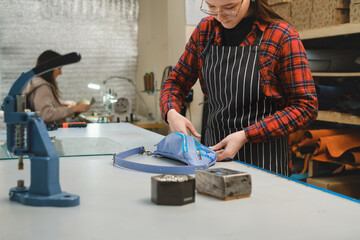 Sewing process. Tailor sewing bag at workshop. Woman creating accessories on workplace. Tailoring concept. Craft from eco leather. Close-up. Production. Small business making leather and canvas bags