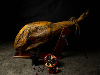 leg of jamon whole with pomegranate and wine on a black background