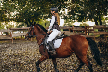 A young beautiful woman jockey is preparing for a show jumping competition. A woman rider rides a...