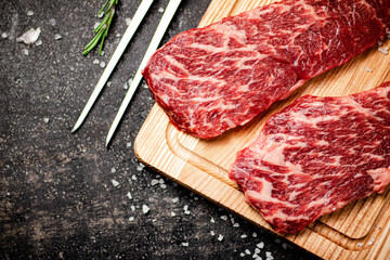 Raw steak on a wooden cutting board. 