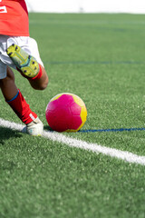 Boy about to kick a soccer ball that is on the grass of the field