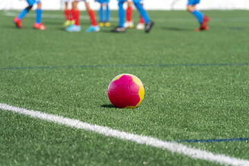 Soccer ball in focus on grass and several legs of some players out of focus