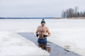 Winter swimming. Woman in frozen lake ice hole. Swimmers wellness and endorphin booster swim in cold water. Beautiful female body tempering Cold winter morning landscape. Biohacking routine