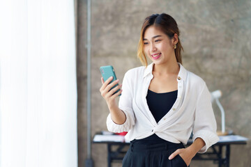 Attractive beautiful Asian woman is using a smartphone to send a message work or play various social and entertainment applications.