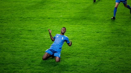Fototapeta na wymiar Championship Match: Blue Soccer Football Team Attack, Player Run Happy after Scoring Goal, Celebrate Victory, Slide on Knees. Sport Channel Broadcast Television Concept.