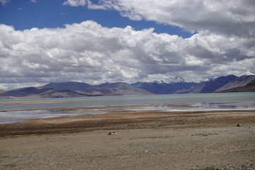 Fototapeta na wymiar Ladakh, India - August 24th, 2022: SUV Car 4x4 In Mountains ove a Beautiful Lake in Ladakh, Tso Moriri