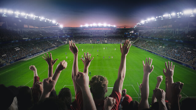 Establishing Shot of Fans Cheer for Their Favorite Team on a Stadium During Soccer Championship Final Match. Teams Play, Crowds of Fans Celebrate Victory, Goal. Live Football Cup Tournament Concept.