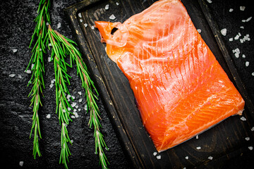 Salted salmon on a cutting board with rosemary. 