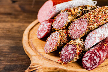 Different types of salami sausage on a wooden cutting board. 