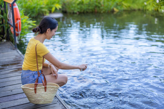 Woman feed the crap fish at water pond