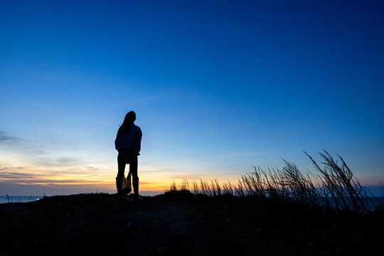 Silhouette of woman stand at the top of the mountain in the evening