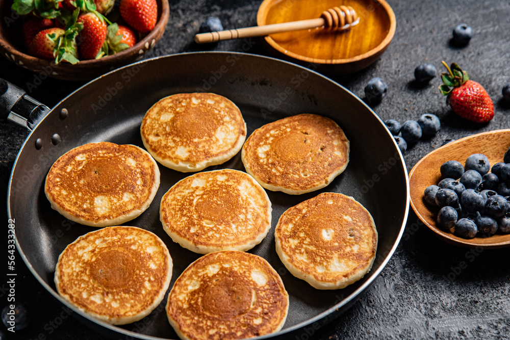 Sticker Pancakes in a frying pan with fresh berries and honey. 