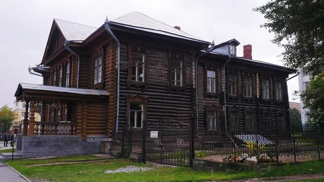 An old wooden house. Stock footage. A large two-storey house made of wood standing without light on the background of a park where citizens walk.