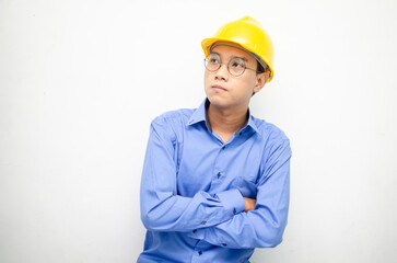 Asian construction worker in blue shirt and yellow safety helmet is seriously thinking with a wondering and thinking gesture and expression.