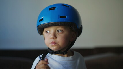 Pensive little boy chewing food wearing protective helmet