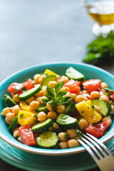 Chickpea salad with tomatoes, cucumber, parsley, onions in a plate, selective focus. Healthy vegetarian food, oriental and Mediterranean cuisine. Chick peas salad