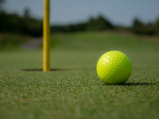 A yellow golf ball in front of a hole