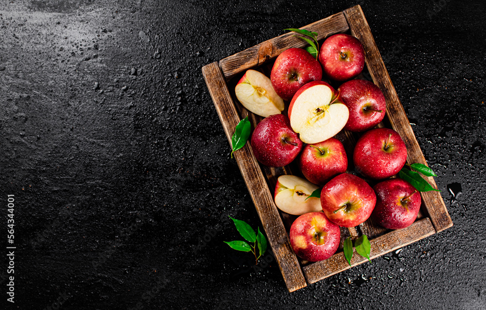 Wall mural pieces and whole red apples on a wooden tray.