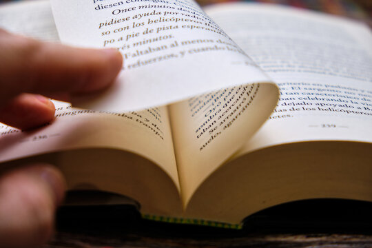 Close-up of a man's hand turning the page of a book.