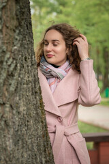 Portrait of a young beautiful long-haired girl in a gray coat in a spring park.