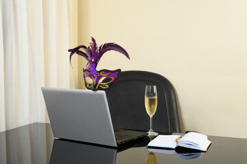 workplace with a laptop on the table a bowl of chapanhe and a carnival mask, carnival holiday